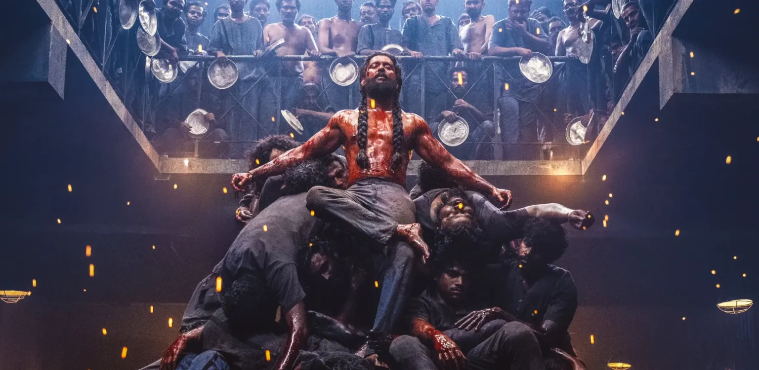 A muscular, blood-stained man with long braided hair sitting triumphantly atop a pile of defeated men in a prison gallery.